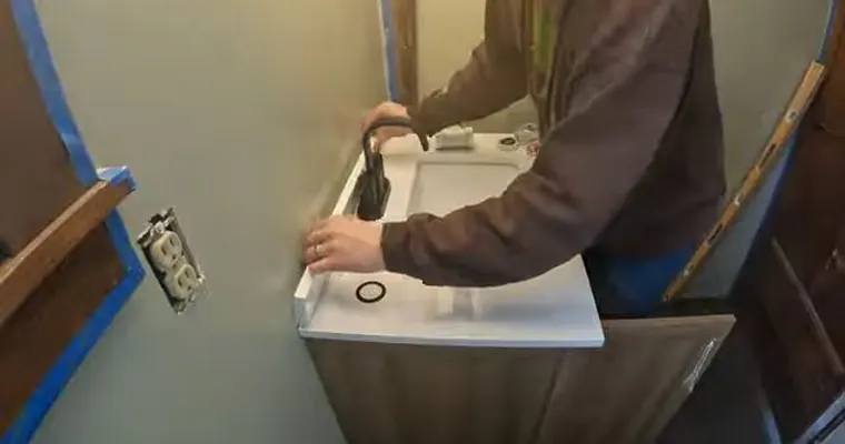 Sink faucet and drain connection being adjusted under a cabinet for Why Tolleson Water Runs 16 to 19 Grains Per Gallon
